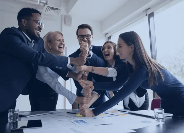 A quintet of remote staff colleagues working in the hospitality industry boosting each other's morale in the workplace, uniting their fists in an upward stack.